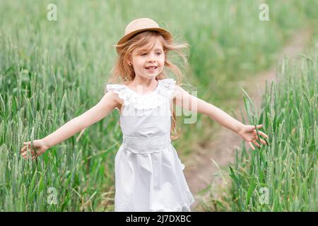 Portrait kleines Mädchen blond auf bei Sonnenuntergang im Feld. Kleines Mädchen, das im Sommer auf dem Feld läuft Stockfoto