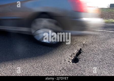 Fahrender Wagen, der nach Überschwemmungen auf der Straße nach Schlagloch fährt, Bognor, West Sussex Stockfoto