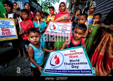 Kalkutta, Indien - am 8. Mai 2022 halten indische Sozialaktivisten zusammen mit ihren Kindern Plakate und entzündeten Kerzen während einer Demonstration, um am Muttertag in Kalkutta auf den Blutzustand und die Thalassämie aufmerksam zu machen. Indische Sozialaktivisten demonstrierten anlässlich des Internationalen Thalassämie-Tages, der ein Datum mit dem Muttertag teilt, um das Bewusstsein für den Blutzustand und die Thalassämie zu schärfen. Der Muttertag wird begangen, um die Existenz der Mütter und ihre Bedeutung im menschlichen Leben zu ehren. Stockfoto