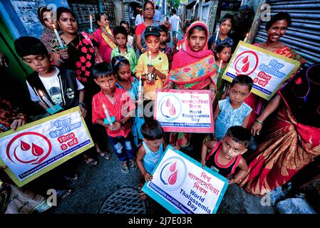 Kalkutta, Indien - am 8. Mai 2022 halten indische Sozialaktivisten zusammen mit ihren Kindern Plakate und entzündeten Kerzen während einer Demonstration, um am Muttertag in Kalkutta auf den Blutzustand und die Thalassämie aufmerksam zu machen. Indische Sozialaktivisten demonstrierten anlässlich des Internationalen Thalassämie-Tages, der ein Datum mit dem Muttertag teilt, um das Bewusstsein für den Blutzustand und die Thalassämie zu schärfen. Der Muttertag wird begangen, um die Existenz der Mütter und ihre Bedeutung im menschlichen Leben zu ehren. Stockfoto