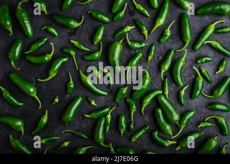 Komposition von hellen grünen Jalapeno Peppers auf schwarzem Beton Hintergrund Stockfoto