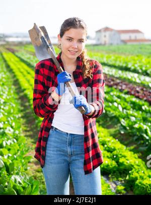 Positive junge Bäuerin im Frühjahr auf dem Gemüsefeld Stockfoto