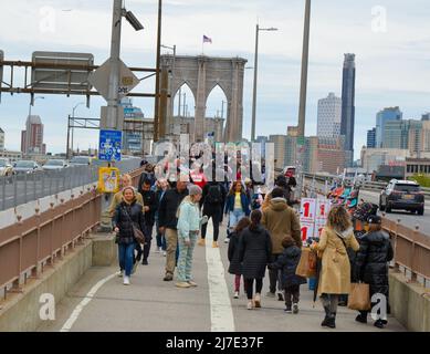 Touristen kommen wieder nach New York City. Am 13. April 2022 läuft eine große Menschenmenge über die Brooklyn Bridge in New York City. Stockfoto