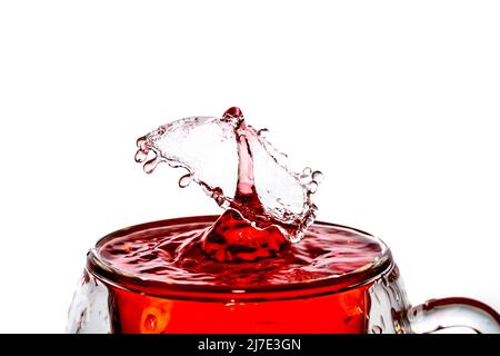 Makroaufnahme einer Fallkollision in einem Glas roten Wassers. Stockfoto