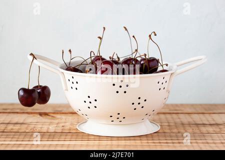 Frische Kirschen in einem weißen Emaille-Sieb Stockfoto