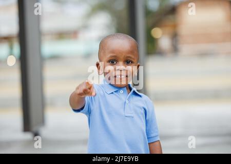 Ein kleiner Junge, der draußen steht und zeigt Stockfoto