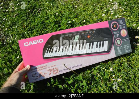 Dortmund, Deutschland - Mai 8 2022: POV-Männerhand mit neuem Casio SA-78-Mini-Keyboard-Klavier im grünen Gartengras Stockfoto