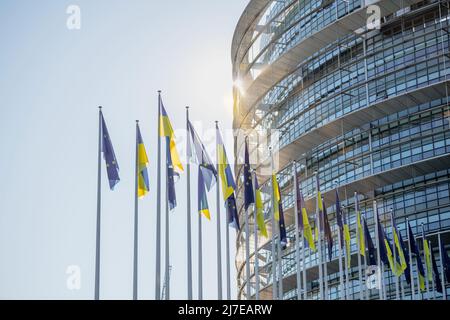 Sonnenstrahlen über der ukrainischen Flagge fliegen neben der Flagge Europas und alle EU-Gewerkschaftsmitglieder Flaggen vor den Büros des Parlamentsgebäudes. Russland setzt seinen Angriff auf die wichtigsten Städte der Ukraine eine Woche nach dem Start einer groß angelegten Invasion des Landes fort Stockfoto