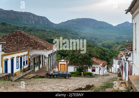 Weite Sicht auf die abschüssige Straße Rua da Camara mit Kopfsteinpflaster und seine kolonialen Häuser im historischen Zentrum von Tiradentes unter wolkenbedecktem Himmel. Stockfoto