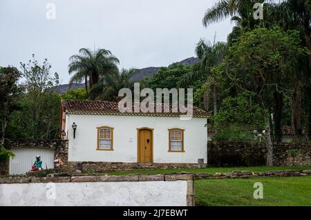 Das Haus des kolonialen Brunnens auf einem kleinen Hügel, umgeben von grüner Vegetation, in der Francisco Candido Barbosa Straße im historischen Zentrum von Tiradentes. Stockfoto