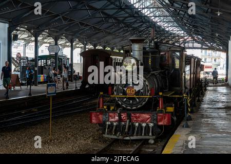 Vorderansicht einer deaktivierten Baldwin Locomotive Works Nº 60, ausgestellt am Bahnhof Sao Joao Del Rei mit einigen dahinter angebrachten Schienenfahrzeugen. Stockfoto