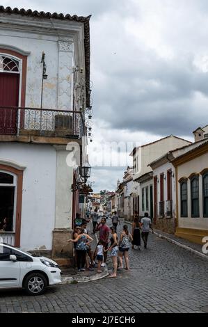 Blick auf die Getulio Vargas Straße mit vielen Fußgängern, die mitten im historischen Zentrum von Sao Joao del Rei unter wolkenverdecktem Himmel herumlaufen. Stockfoto