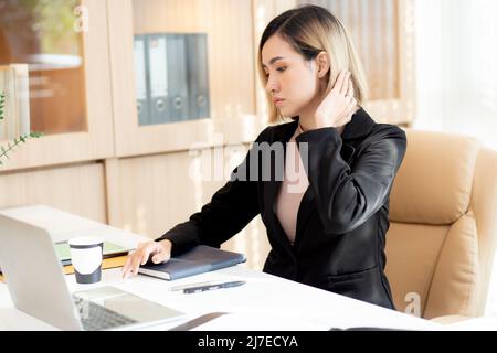 Junge asiatische Frau, die im Büro an einem Laptop arbeitet, Angestellte oder Manager arbeiten am Arbeitsplatz mit Selbstvertrauen, Geschäftsfrau mit Notebook Stockfoto