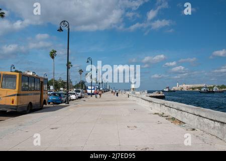 Touristen, die auf dem Malecon in Havanna, Kuba, spazieren gehen. Die Malecón ist eine breite Esplanade, eine Straße und eine Ufermauer, die sich über 8 km entlang der Küste im Hafen erstreckt Stockfoto