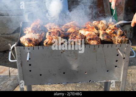 Nahaufnahme der Spieße beim Kochen auf dem Grill mit Rauch. Stockfoto