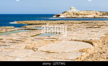 Blick über die Xwejni-Salzpfannen auf den gelben Xwejni-Felsen auf der Insel Gozo auf Malta. Stockfoto
