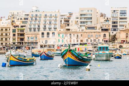 Im April 2022 vertäuten farbenfrohe Boote in der Bucht von Spinola in der Nähe der maltesischen Hauptstadt Valletta. Stockfoto