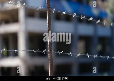 Stacheldrahtzaun vor dem Gefängnisgebäude in der Nähe Stockfoto