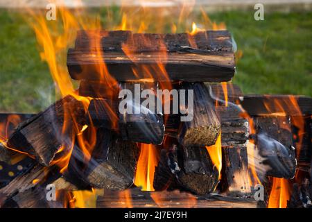 Auf der Straße brennt Feuer, Holz, verkohltes Feuerholz und Orangenflamme Stockfoto