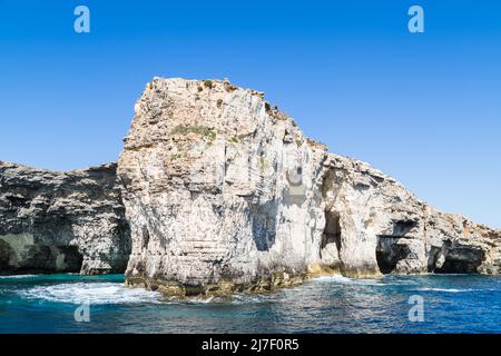 Wellen schlagen gegen Klippen und Meereshöhlen auf der Insel Comino, Malta. Stockfoto