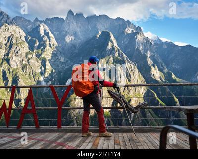 Rückansicht des asiatischen Wandertrekers mit Spazierstock, der auf der Aussichtsplattform steht und auf den Berg blickt Stockfoto