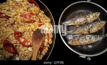 In zwei Pfannen gekochte Sardinen mit Sapnish-Migas. Hoher Betrachtungswinkel Stockfoto