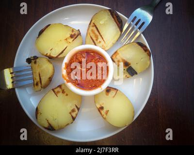 Moderne Küche Tapas, geröstete Potatos mit roter Chimichurri-Sauce. Ansicht von oben Stockfoto