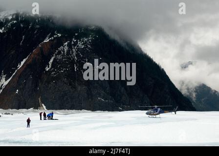 Touristen und ihr Transporthubschrauber auf dem Mendenhall-Gletscher, in der Nähe von Juneau. Stockfoto