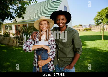 Gemischte Rassen, männliche und weibliche Bauern, die im Freien lächelnd stehen Stockfoto