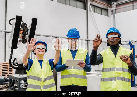 Multirassische Ingenieure mit Augmented Reality futuristische Brille in der Automatisierungs- und Roboterfabrik - Neues Konzept für Industrietechnologie Stockfoto