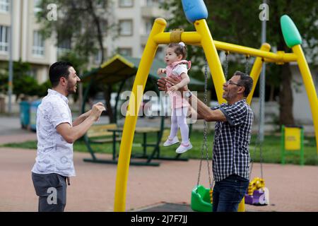 1. Mai 2022, Gaziantep, Türkei: Gaziantep, Türkei. 01 Mai 2022. Der syrische Großvater Kamal Khatib spielt mit seinem Enkelkind auf einem Spielplatz in Gaziantep. Kamal und sein Sohn Bashir wurden getrennt, als Kamal aus dem Krieg floh, um in Jordanien Zuflucht zu suchen. Erst 10 Jahre später, als Kamal in die Türkei reisen konnte, um sich wegen seiner sehr aggressiven Krebsform behandeln zu lassen, kam er mit seinem Sohn wieder zusammen, der jetzt mit seiner Frau und zwei kleinen Kindern in der Türkei lebt. Die Veranstaltung beleuchtet die Tragödie des Krieges in Syrien, bei dem die Syrer in einem nie endenden Konflikt gefangen sind und große Verluste, Vertreibung, und ein verursachen Stockfoto