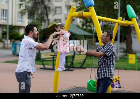 1. Mai 2022, Gaziantep, Türkei: Gaziantep, Türkei. 01 Mai 2022. Der syrische Großvater Kamal Khatib spielt mit seinem Enkelkind auf einem Spielplatz in Gaziantep. Kamal und sein Sohn Bashir wurden getrennt, als Kamal aus dem Krieg floh, um in Jordanien Zuflucht zu suchen. Erst 10 Jahre später, als Kamal in die Türkei reisen konnte, um sich wegen seiner sehr aggressiven Krebsform behandeln zu lassen, kam er mit seinem Sohn wieder zusammen, der jetzt mit seiner Frau und zwei kleinen Kindern in der Türkei lebt. Die Veranstaltung beleuchtet die Tragödie des Krieges in Syrien, bei dem die Syrer in einem nie endenden Konflikt gefangen sind und große Verluste, Vertreibung, und ein verursachen Stockfoto