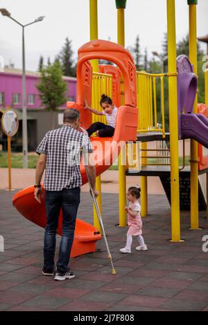 1. Mai 2022, Gaziantep, Türkei: Gaziantep, Türkei. 01 Mai 2022. Der syrische Großvater Kamal Khatib spielt mit seinem Enkelkind auf einem Spielplatz in Gaziantep. Kamal und sein Sohn Bashir wurden getrennt, als Kamal aus dem Krieg floh, um in Jordanien Zuflucht zu suchen. Erst 10 Jahre später, als Kamal in die Türkei reisen konnte, um sich wegen seiner sehr aggressiven Krebsform behandeln zu lassen, kam er mit seinem Sohn wieder zusammen, der jetzt mit seiner Frau und zwei kleinen Kindern in der Türkei lebt. Die Veranstaltung beleuchtet die Tragödie des Krieges in Syrien, bei dem die Syrer in einem nie endenden Konflikt gefangen sind und große Verluste, Vertreibung, und ein verursachen Stockfoto