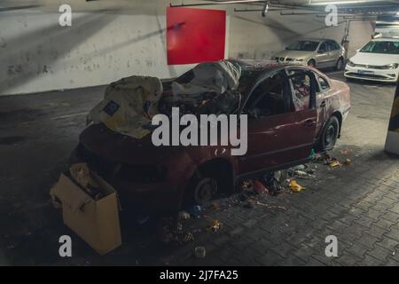 Die Vorderseite eines verlassenen Autos voller Staub, schmutzig mit kaputten Bildschirmen und flachen Reifen, die als Müllkippe in der Tiefgarage verwendet wurden. Hochwertige Fotos Stockfoto