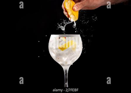 Eine Zitrone in ein Glas Gin Tonic quetschen Stockfoto