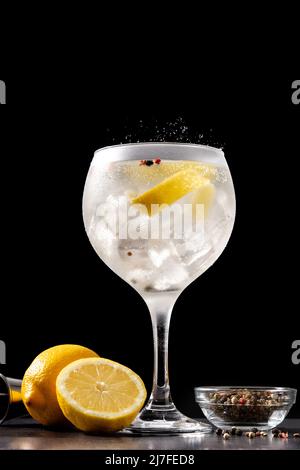 Gießen Sie Gin Tonic Drink in ein Glas auf schwarzem Hintergrund Stockfoto