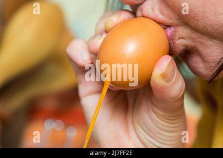 Nahaufnahme einer Frau, die zu ostern ein Ei ausbläst Stockfoto