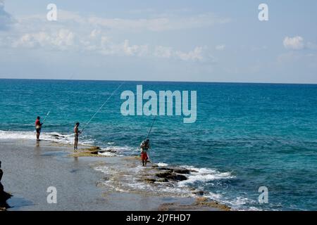 Felsformation und Fischer am Strand von Dor-Habonim, Israel Stockfoto