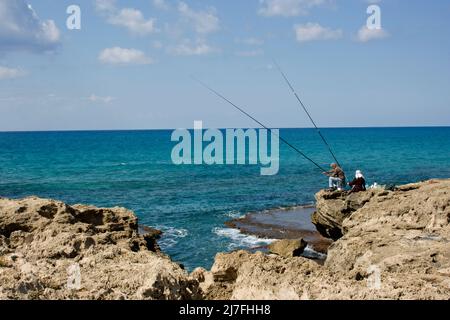 Felsformation und Fischer am Strand von Dor-Habonim, Israel Stockfoto