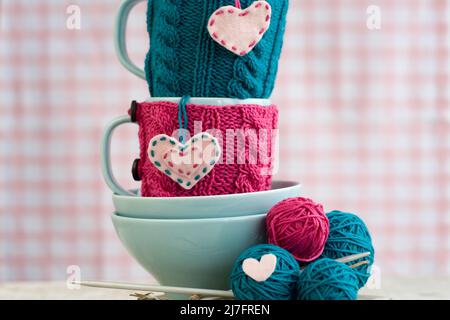Helle Garnkugeln in blauen Tellern und handgefertigt aus Filzherz Stockfoto