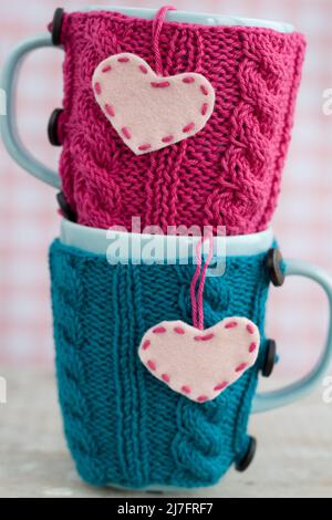 Zwei blaue Cups in blau-rosa Pullover mit Filzherzen Stockfoto