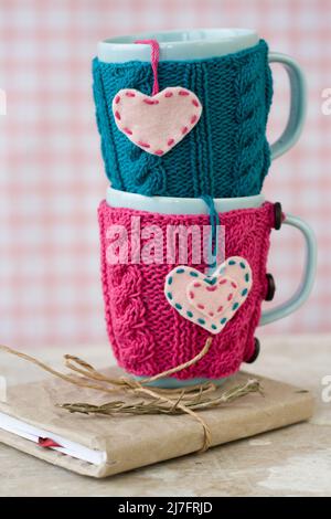 Zwei blaue Cups in blau-rosa Pullover mit Filzherzen Stockfoto