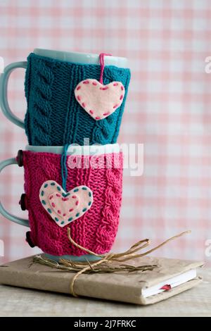 Zwei blaue Cups in blau-rosa Pullover mit Filzherzen Stockfoto