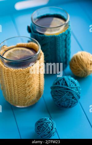 Zwei Tassen Tee in Gelb Strickpullover auf blauem Hintergrund Stockfoto