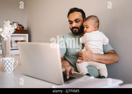 Vater mit Baby, die von zu Hause aus arbeiten Stockfoto