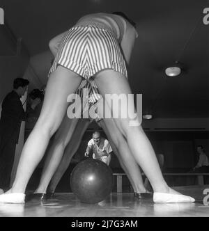 Bowling in der 1950s. Ein Mann mit drei jungen Frauen in einer Bowlingbahn. Sie sind mit kurzen gestreiften Röcken und Pullovern gekleidet. Die drei Mädchen sind alle Theaterschauspielerinnen: Ingrid Björk, UllaCarin Rydén und Brita Ulfberg. Ewert Ekström zeigt, dass sie beim Bowling unterrichtet werden. Er war ein professioneller Bowler Spieler in der 1930s und ist zu dieser Zeit ein Lehrer und Besitzer des Bowling-Club. 1950. Schweden Kristoffersson Ref. AY36-2 Stockfoto