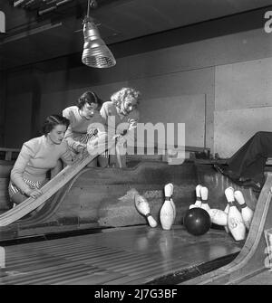 Bowling in der 1950s. Zum ersten Mal bowlen drei Mädchen. Sie sind in kurze gestreifte Röcke und Springer gekleidet und im Bereich der Fahrbahn abgebildet, wo sich die Bowlingstifte genau in dem Moment befinden, in dem der Bowlingball einen Schlag trifft. Die drei Mädchen sind alle Theaterschauspielerinnen: Ingrid Björk, UllaCarin Rydén und Brita Ulfberg. Zu diesem Zeitpunkt diese Bowlingbahn haben keine Maschinen, die die Bowling-Pins hebt. Stattdessen wurden Menschen als Nadelhalter eingesetzt und die Beine einer solchen Person werden nach rechts gesehen, da er seine Beine in der Luft hat, um zu vermeiden, von der Bowlingkugel oder den Nadeln getroffen zu werden. 1950 Stockfoto