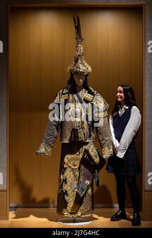 London, Großbritannien. 9 Mai 2022. Ein Mitarbeiter posiert mit „Einem seltenen Anzug der zeremoniellen Rüstung mit Helm und Köcher“, Ende der Qing-Dynastie (geschätzt. £10.000 - £15.000) bei einer Vorschau auf Bonhams Verkauf von Fine Chinese Art in ihrer New Bond Street Galerie. Chinesische jades, Keramik, Lackwaren, Imperial- und Hoftextilien sowie Kunstwerke werden am 12. Mai zum Verkauf angeboten. Kredit: Stephen Chung / Alamy Live Nachrichten Stockfoto