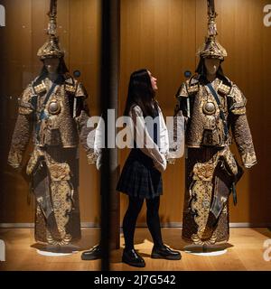 London, Großbritannien. 9 Mai 2022. Ein Mitarbeiter posiert mit „Einem seltenen Anzug der zeremoniellen Rüstung mit Helm und Köcher“, Ende der Qing-Dynastie (geschätzt. £10.000 - £15.000) bei einer Vorschau auf Bonhams Verkauf von Fine Chinese Art in ihrer New Bond Street Galerie. Chinesische jades, Keramik, Lackwaren, Imperial- und Hoftextilien sowie Kunstwerke werden am 12. Mai zum Verkauf angeboten. Kredit: Stephen Chung / Alamy Live Nachrichten Stockfoto