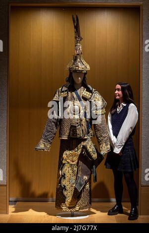 London, Großbritannien. 9 Mai 2022. Ein Mitarbeiter posiert mit „Einem seltenen Anzug der zeremoniellen Rüstung mit Helm und Köcher“, Ende der Qing-Dynastie (geschätzt. £10.000 - £15.000) bei einer Vorschau auf Bonhams Verkauf von Fine Chinese Art in ihrer New Bond Street Galerie. Chinesische jades, Keramik, Lackwaren, Imperial- und Hoftextilien sowie Kunstwerke werden am 12. Mai zum Verkauf angeboten. Kredit: Stephen Chung / Alamy Live Nachrichten Stockfoto